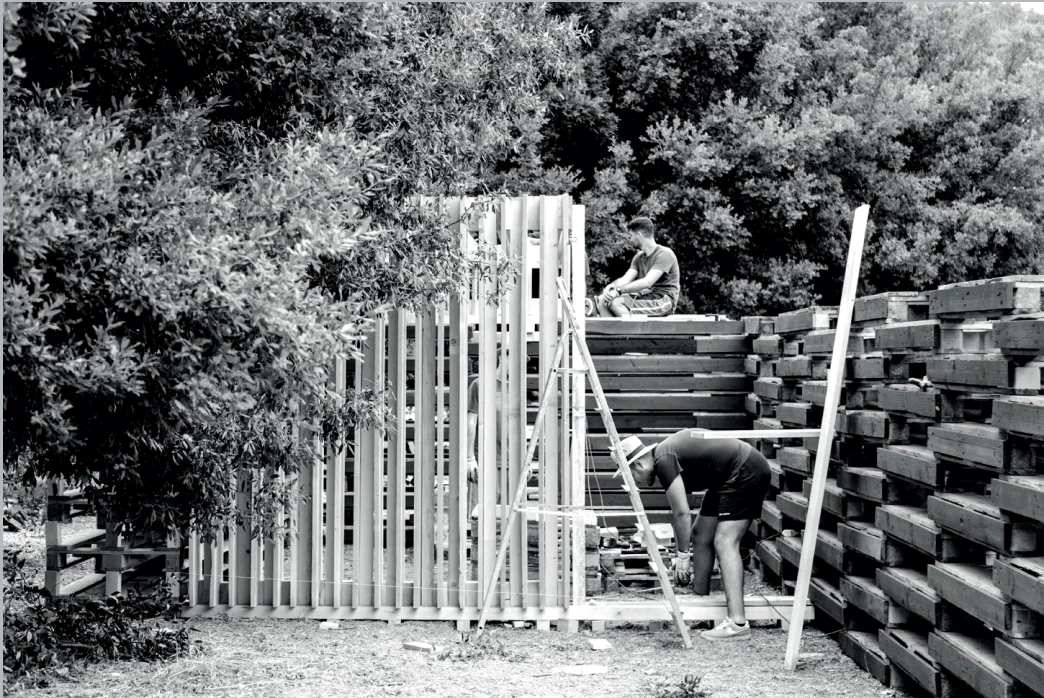 Il gruppo monta una struttura verticale accanto a una catasta di pallet.